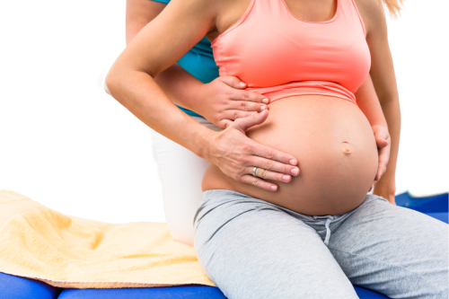Femme enceinte recevant un soin physiothérapique par un travail abdominal.